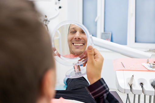 Wesley Chapel Man Smiling in the Mirror After Getting Implant Bridges