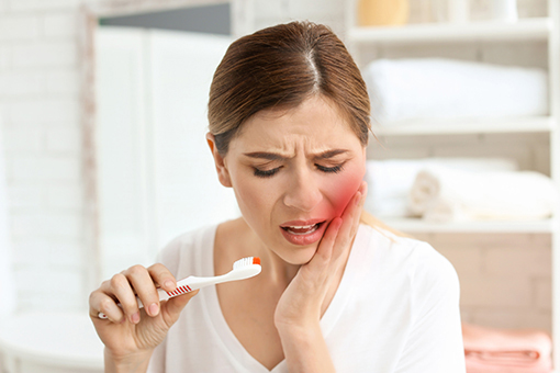 Woman In Pain While Brushing Teeth In Need of Tooth Extraction in Wesley Chapel Florida